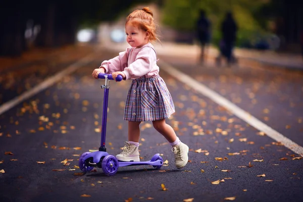 可爱的红头发女婴在秋天的公园里滑行 — 图库照片
