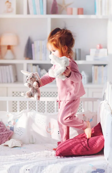 可愛いです幼児赤ちゃん女の子楽しいですぬいぐるみを遊んでベッドで保育室 — ストック写真