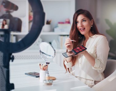 Güzel genç bir kadın evden bir güzellik bloğu yayınlıyor, çevrimiçi içerik yaratıcısı makyaj yapıyor.