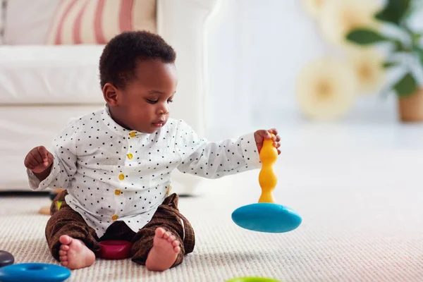 かわいい赤ちゃんの男の子が家でカーペットの上で輪を積みながら遊んでいます — ストック写真