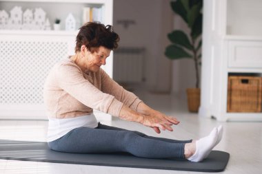 Atletik olgun kadın evde egzersiz yapıyor, aktif yaşam tarzı, 84 yaşında bayan sporu yapıyor.
