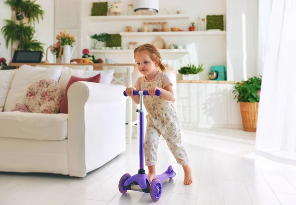 Feliz Bebé Niña Divirtiéndose Montando Scooter Casa Espacio Abierto Sala — Foto de Stock