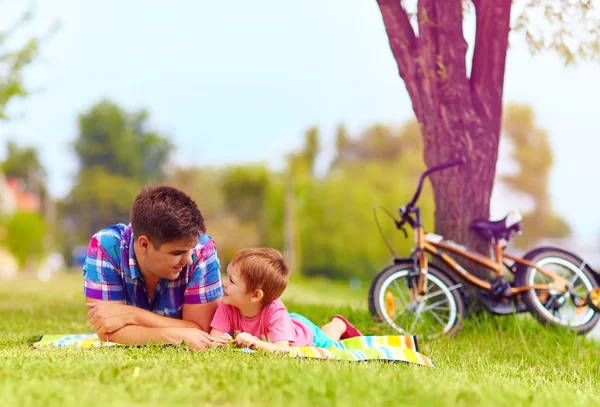 Padre e figlio si rilassano dopo un giro in bicicletta nel parco cittadino — Foto Stock