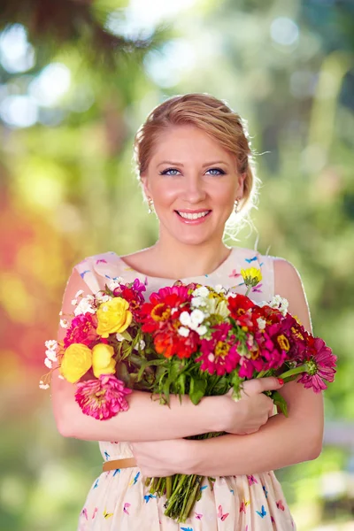 Kucak dolusu kır çiçekleri ile güzel Bayan — Stok fotoğraf