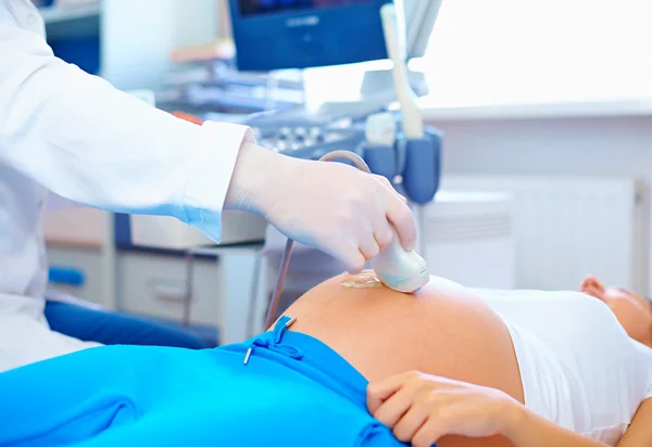 Doctor conducting the ultrasound procedure to pregnant woman — Stock Photo, Image