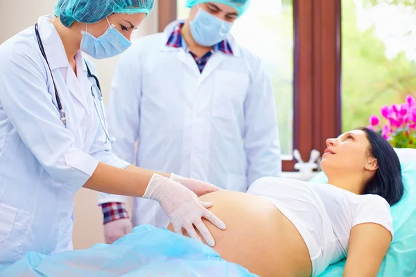 Doctor palpates the abdomen of pregnant woman during childbirth — Stock Photo, Image