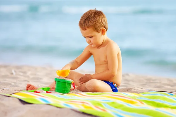 Cute kid playing with toys in sand on the beach — Stock Photo, Image