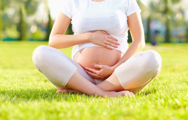 belly of pregnant woman in summer park clipart