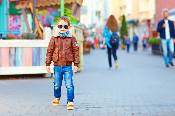 Стильный счастливый мальчик, идущий по многолюдной улице — стоковое фото