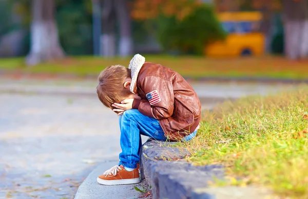 Enfant bouleversé garçon assis seul dans le parc de la ville — Photo