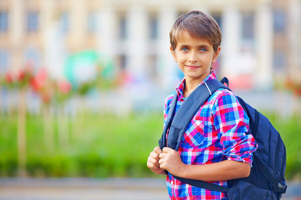 portrait of cute schoolboy with backpack, outdoors