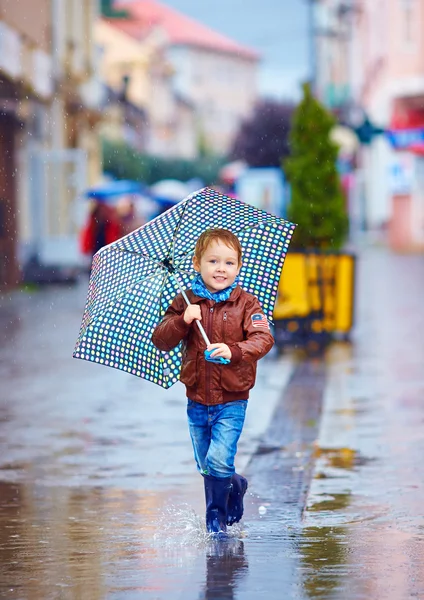 Lindo niño, niño caminando en charco en la ciudad lluviosa —  Fotos de Stock