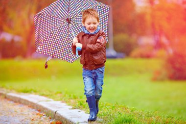 happy boy running under an autumn rain clipart
