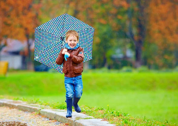 Menino feliz correndo sob uma chuva de outono — Fotografia de Stock