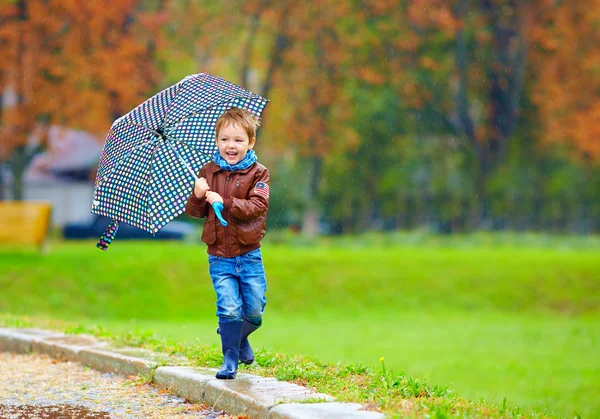 快乐的男孩，在秋天的雨下运行 — 图库照片