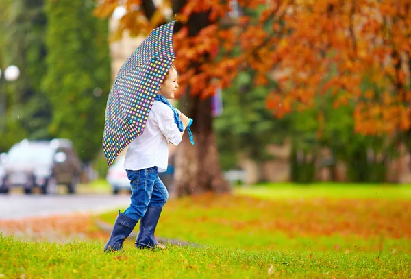 Lindo niño disfrutando de una lluvia de otoño en el parque de la ciudad —  Fotos de Stock