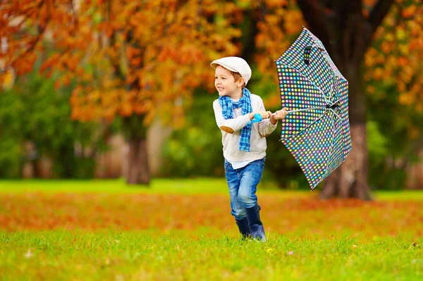 Счастливый мальчик наслаждается осенним дождем в парке — стоковое фото
