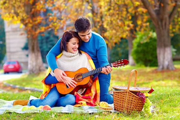 Man teaching girl play a guitar on autumn picnic — Stock Photo, Image