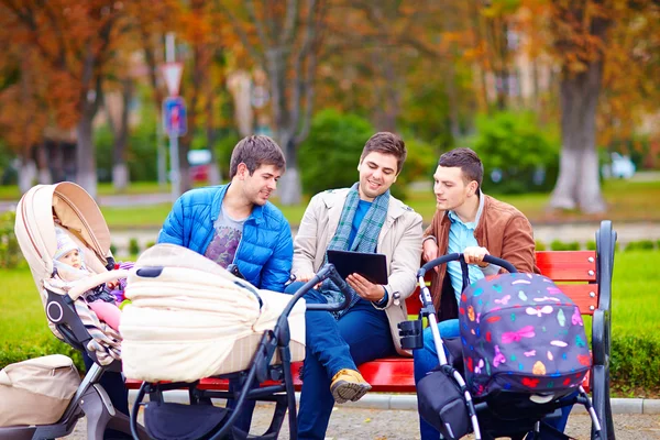 Tre glada fäder med barnvagnar i stadsparken — Stockfoto