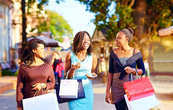 Glada afrikanska flickor promenader på gatan med shoppingväskor — Stockfoto