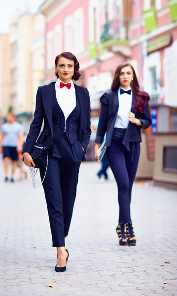 Meninas bonitas em ternos pretos andando na rua — Fotografia de Stock