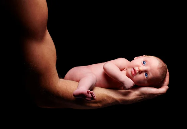 Tiny newborn baby in strong father's hand Stock Picture