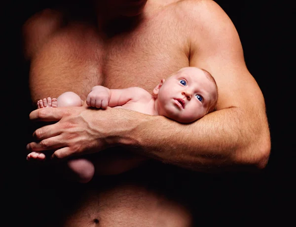 Diminuto bebé recién nacido en la mano de un padre fuerte —  Fotos de Stock