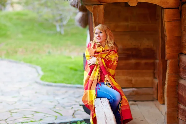 Positive woman enjoying autumn, wrapping herself in warm blanket - Stock-foto