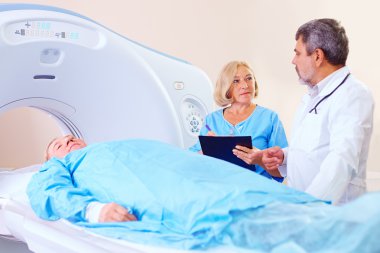 doctor instructing medical staff about CT scanner procedure clipart