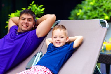 Baba ve oğul rahatlatıcı tatil şezlong üzerinde
