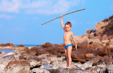cute boy with bamboo spear pretends like he is aborigine on desert island clipart