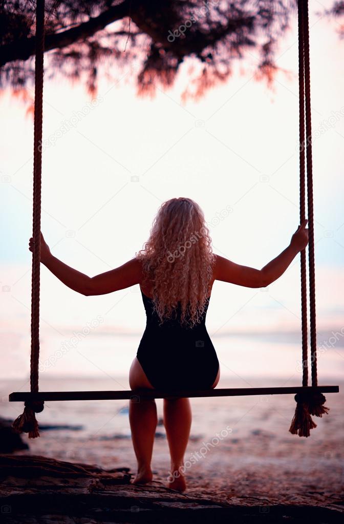 young woman sitting on tree wings at the beach