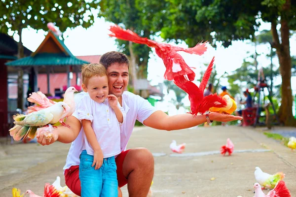 Familia feliz alimentación coloridas palomas en granja de animales — Foto de Stock