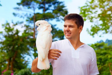 young man, ornithologist holding gorgeous cockatoo parrot clipart