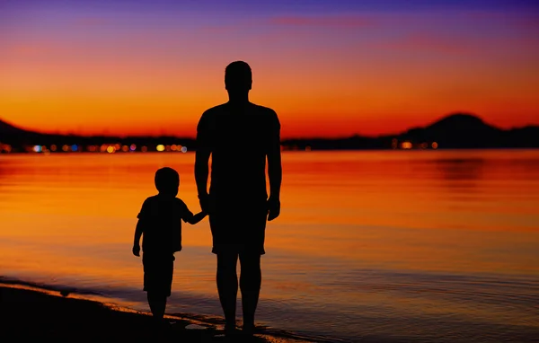 Otec a syn u okraje vody při západu slunce — Stock fotografie