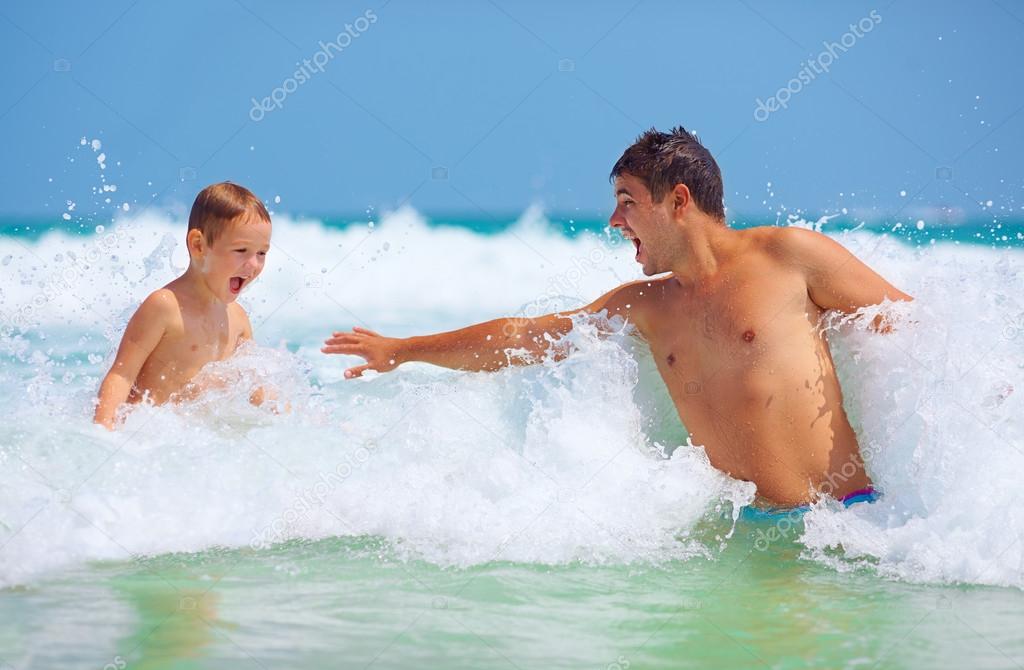 happy father and son jumping in waves, summer vacation
