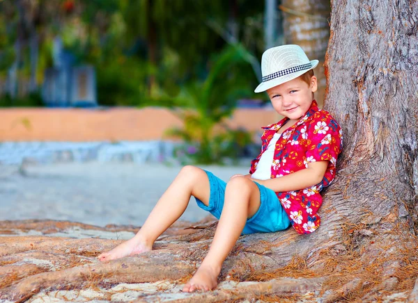 Leuke trendy jongen in de buurt van de boom op het strand — Stockfoto