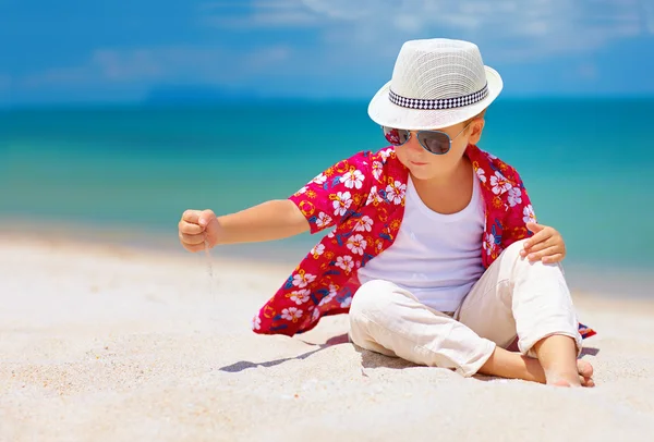 Stijlvolle jongen, jongen spelen met zand op zomer strand — Stockfoto