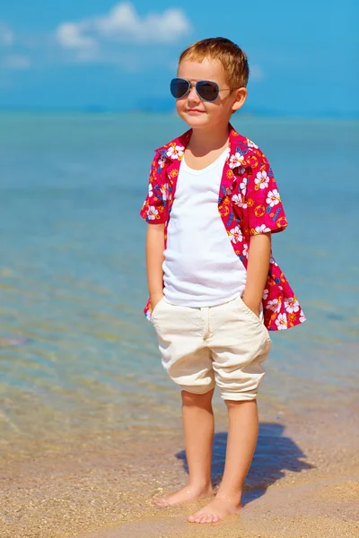 Happy stylish boy standing in water on tropical beach — Stock Photo, Image