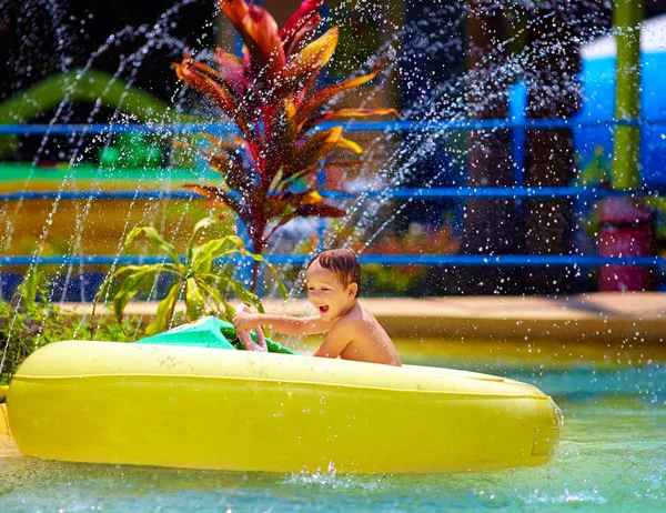 Niño feliz conduciendo barco de agua de juguete en el parque acuático — Foto de Stock