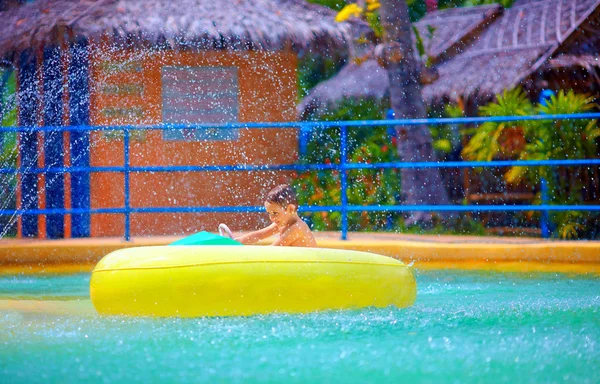 Bambino felice che guida la barca dell'acqua del giocattolo in parco dell'acqua — Foto Stock