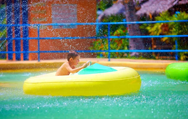 Garoto feliz dirigindo barco de água de brinquedo no parque aquático — Fotografia de Stock