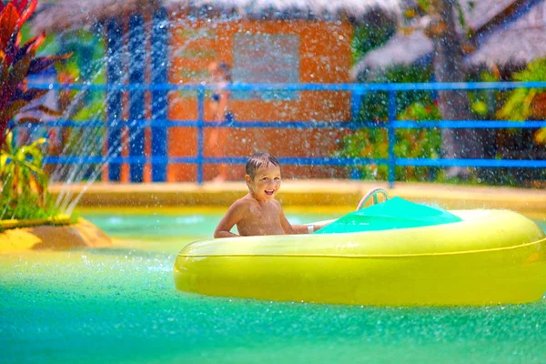 Garoto feliz dirigindo barco de água de brinquedo no parque aquático — Fotografia de Stock