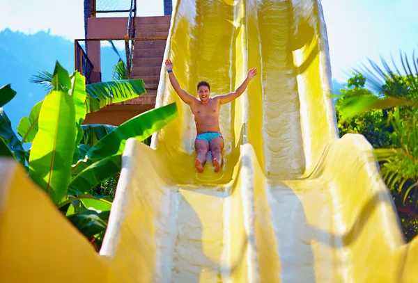 Hombre excitado divertirse en tobogán de agua en parque acuático tropical — Foto de Stock