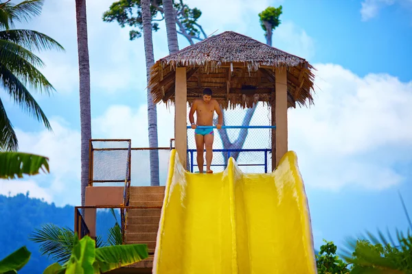 Man having fun on water slide in tropical aqua park — Stock Photo, Image