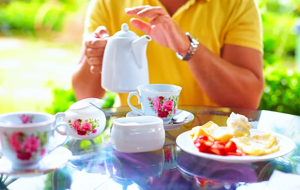 Man häller engelskt te Cup, på sommaren garden — Stockfoto