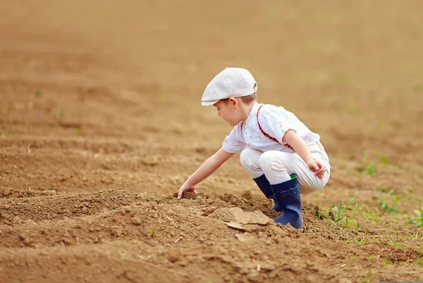 Cute little farmer spuding the soil on spring field Royalty Free Stock Images