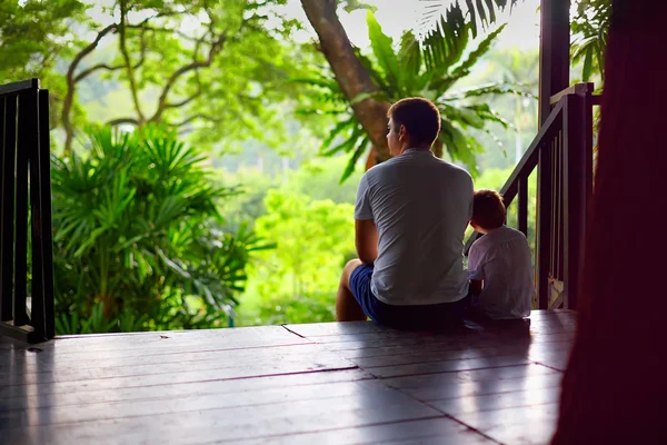Padre e hijo sentado en las escaleras de la casa del árbol en el bosque tropical — Foto de Stock