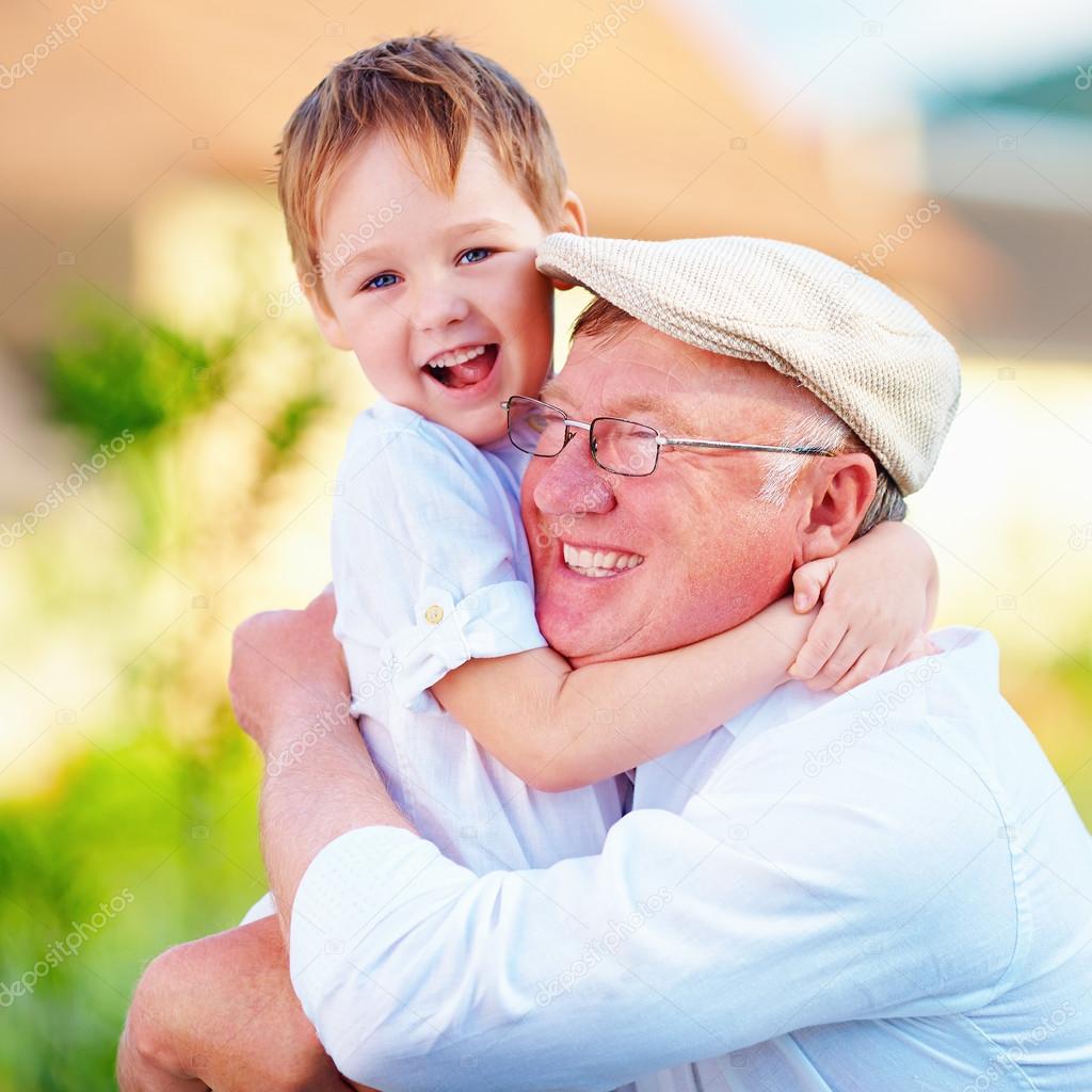 portrait of happy grandpa and grandson embracing outdoors