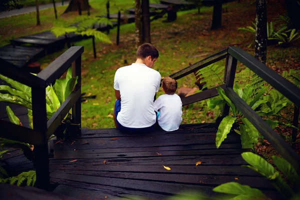 Pai e filho sentado em escadas de madeira na floresta tropical — Fotografia de Stock